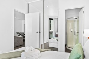 A hotel room with a bed, a shower, a seating area, and a bathroom. - City Centre Living Meets Comfort by Zodiak (Auckland)