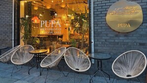 Ein Restaurant namens Pupa mit Außenbereich und einer Ziegelwand.