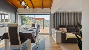Ein modernes Wohnzimmer mit Essbereich, Holzboden und Blick ins Freie.