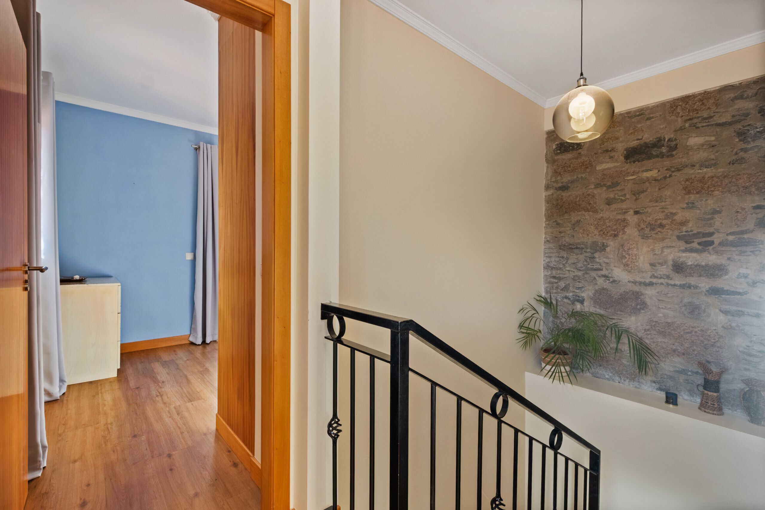 Un escalier avec un mur en pierre et un luminaire suspendu.