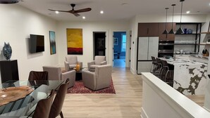 Una sala moderna con una mesa de comedor de vidrio, asientos cómodos y un ventilador de techo.