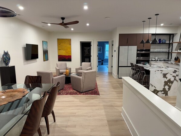Un salon moderne avec une table à manger en verre, des sièges confortables et un ventilateur de plafond.