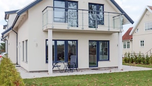 A modern two-story house with a balcony, large windows, and a visible outdoor seating area. - 5 Star Holiday Home in Falkenberg (Falkenberg)