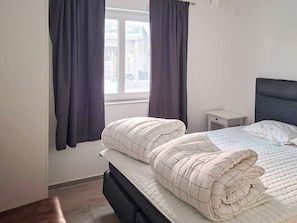 A bedroom with a bed, a nightstand, a window with curtains, and a view of the outside. - 5 Star Holiday Home in Falkenberg (Falkenberg)