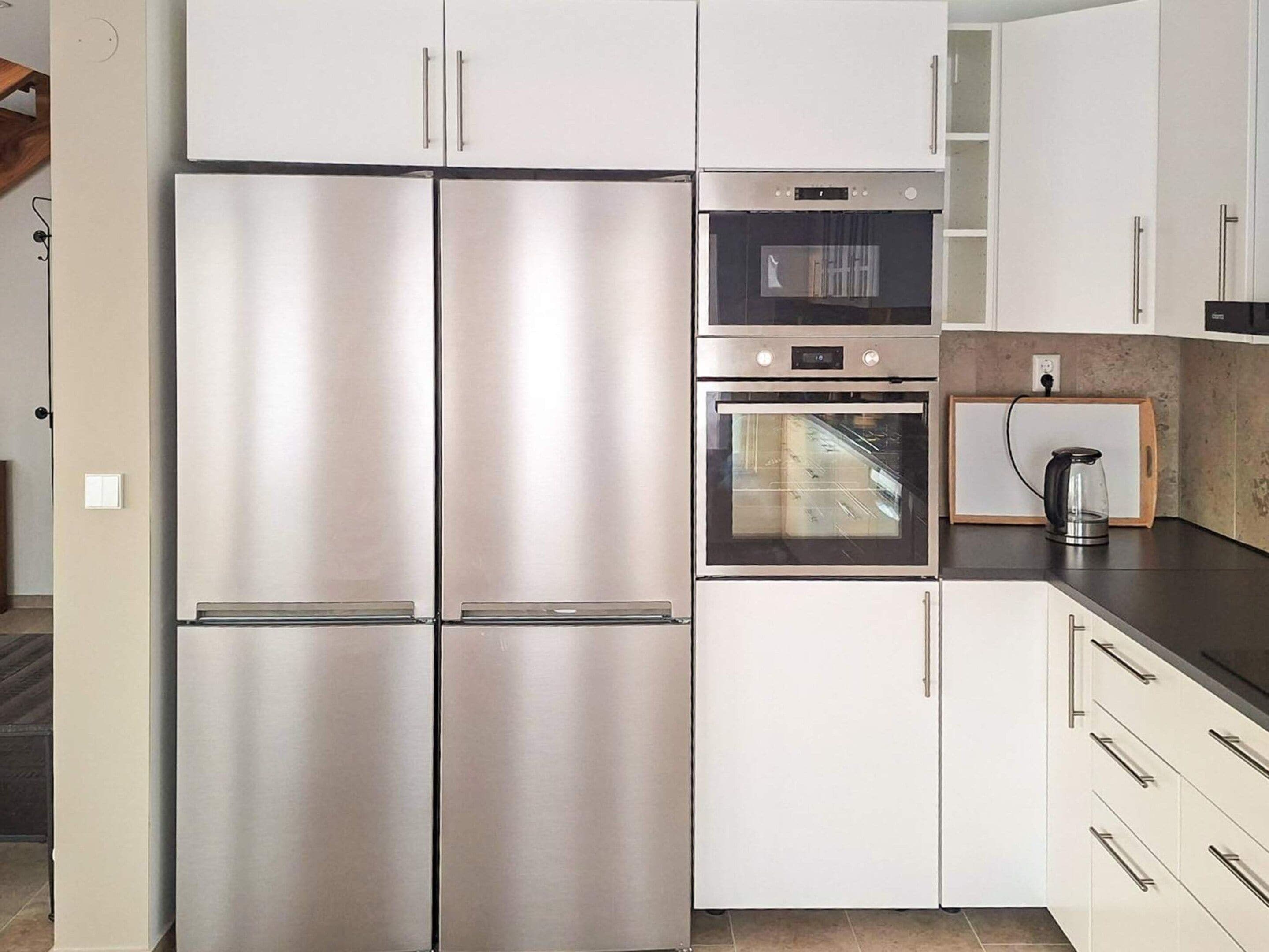 Una cocina con electrodomésticos de acero inoxidable, que incluye un refrigerador doble, un microondas y un horno.
