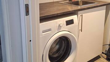 Cocina compacta y moderna con lavadora integrada, un lavabo y una encimera.