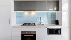Una cocina moderna con armarios blancos, estufa integrada, microondas y cafetera.