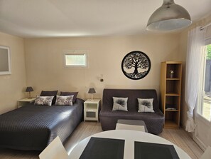 Une chambre à coucher comprenant un lit, un canapé, une table de chevet, une œuvre d’art murale et une bibliothèque.