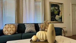 A living room with a dark green sofa, patterned cushions, a white coffee table with a marble top, a vase with dried flowers, and a framed painting on the wall. - South Jersey Shore Comfort & Relaxing  Retreat in Absecon, near  Atlantic City (Absecon)