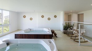 A modern spa room with two hot tubs, wooden flooring, and a seating area with rocking chairs. - Apartamento premium a 1 minuto de la playa con todas las comodidades (Magdalena)