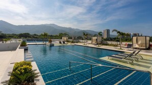 A swimming pool with multiple lanes, sun loungers, and a view of mountains in the background. - Apartamento premium a 1 minuto de la playa con todas las comodidades (Magdalena)