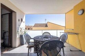 A balcony with a round table, chairs, and a small table with a drying rack. - Appartement lumineux avec balcon a Valras Plage (Valras-Plage)