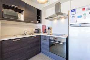 Una cocina moderna con armarios de madera oscura, un refrigerador de acero inoxidable, horno empotrado y microondas.