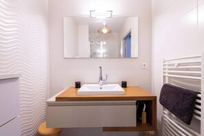 A modern bathroom with a white sink, wooden countertop, and a mirror above it. - Appartement lumineux avec balcon a Valras Plage (Valras-Plage)