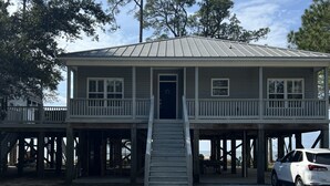A two-story house with a porch, a front door, and a staircase leading to the entrance. - Bayfront home with private pier & dock- near Fairhope & Magnolia Springs (Foley)