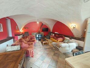 Un salon chaleureux avec une cheminée, des murs rouges et une table à manger en bois.