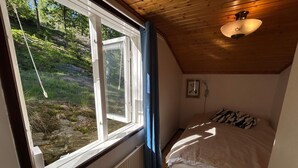 A bedroom with a large window, a bed, a radiator, and a ceiling light fixture. - 4 Person Holiday Home in Henan (Henån)