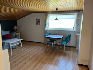 A room with a wooden ceiling, a window with curtains, a table with chairs, and a bed with pillows. - 4 Person Holiday Home in Henan (Henån)