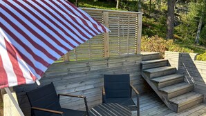 A deck with outdoor furniture, including two chairs and a table, and a wooden staircase. - 4 Person Holiday Home in Henan (Henån)