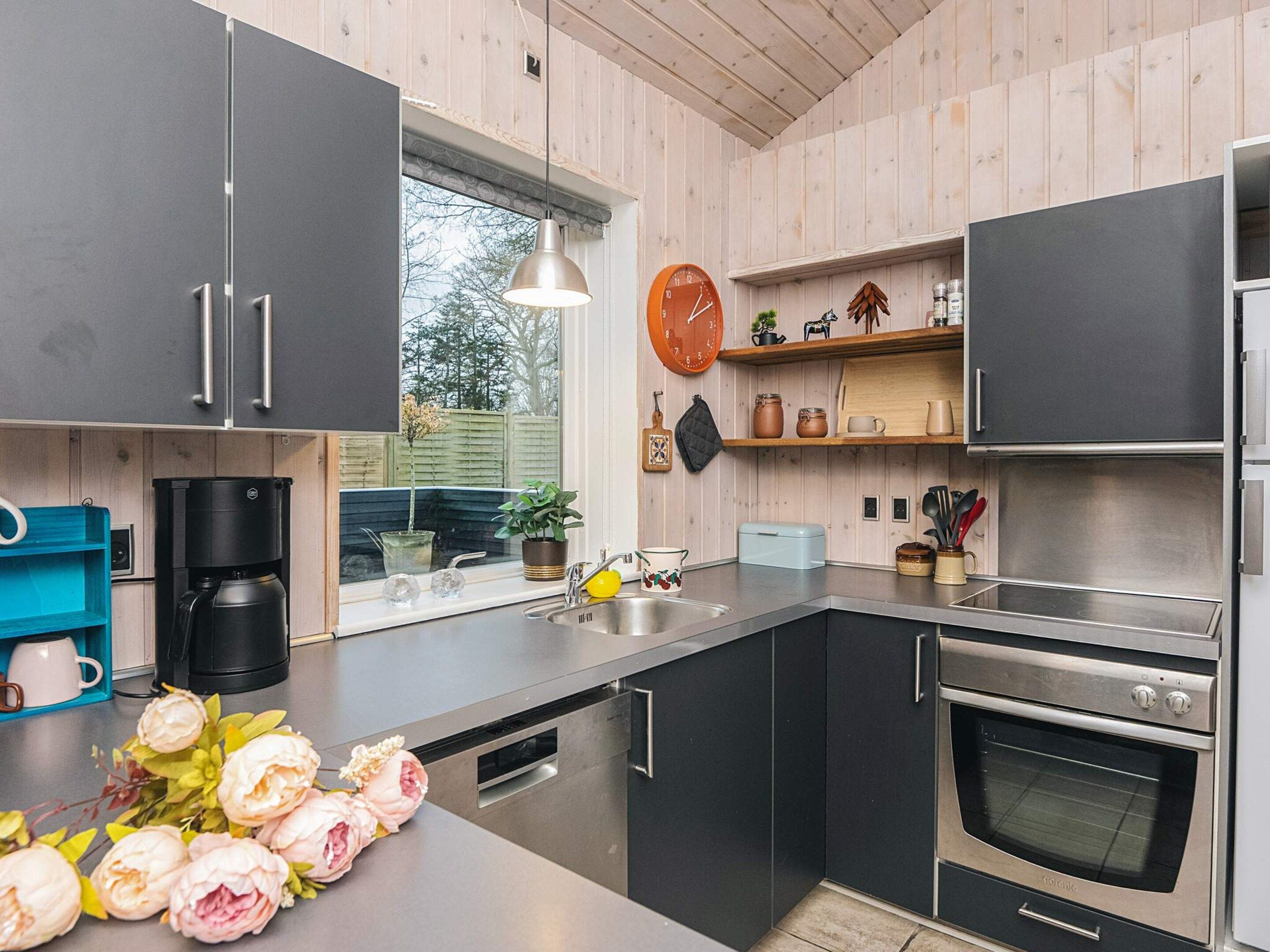 A modern kitchen with dark cabinets, a coffee maker, a toaster, and a built-in oven.