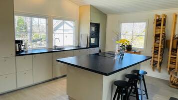 Una cocina moderna con una isla grande, taburetes de bar y vistas al exterior.