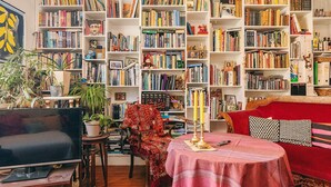 Een gezellige woonkamer met een televisie, een rode bank, een salontafel en een boekenplank vol boeken.