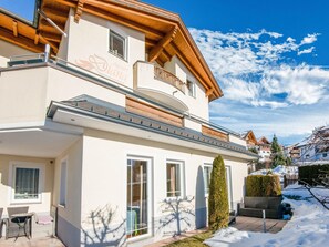A two-story building with a balcony, a patio with outdoor furniture, and a snow-covered ground. - Apartment in Tyrol in an Attractive Area (Fiss)