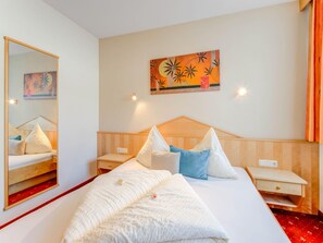 A hotel room with a large bed, a bedside table, a nightstand, a mirror, and a wall painting. - Apartment in Tyrol in an Attractive Area (Fiss)