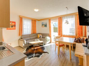 A modern living room with a sofa, dining table, and kitchen area. - Apartment in Tyrol in an Attractive Area (Fiss)