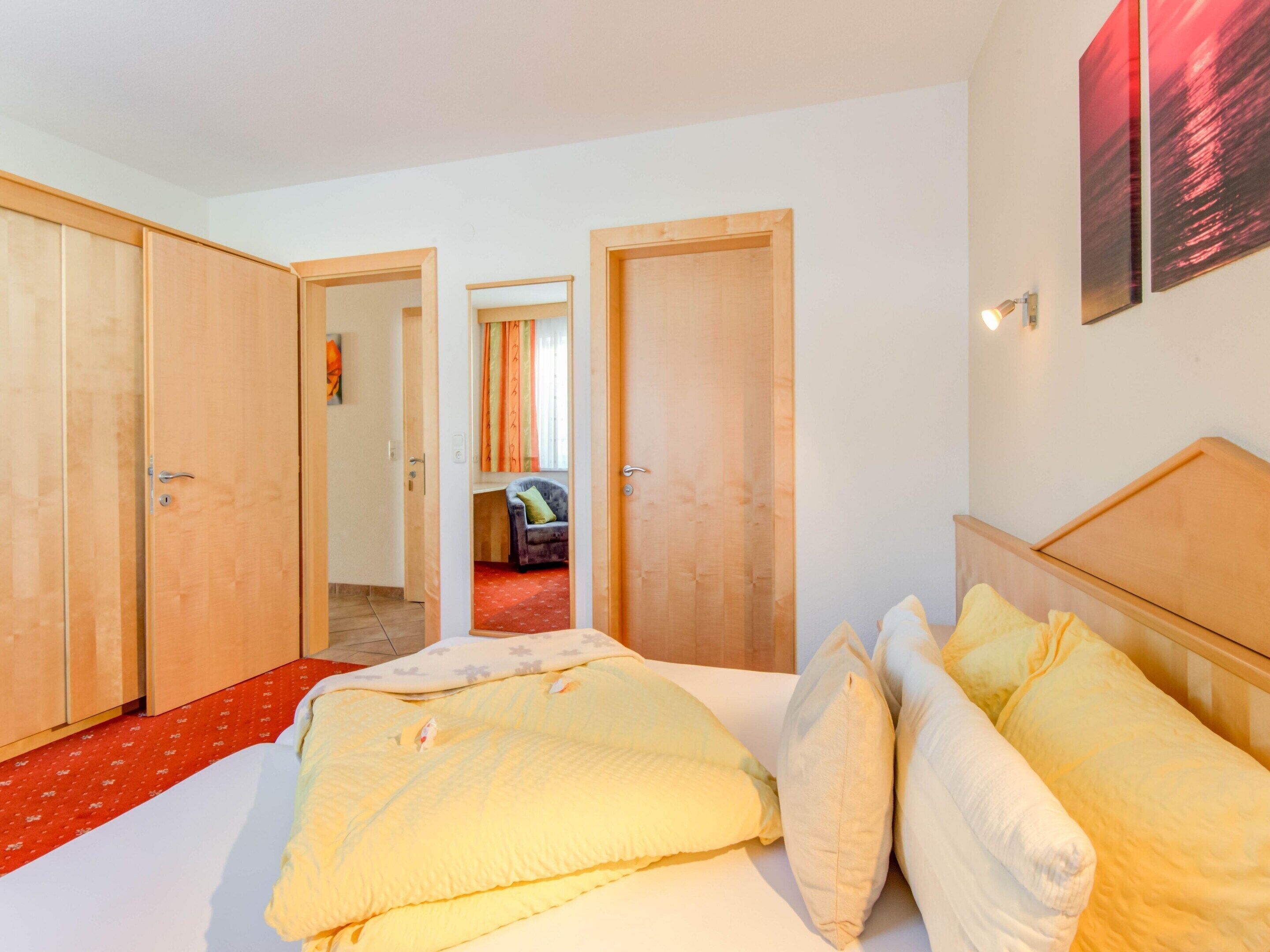 Ein Schlafzimmer mit einem Bett, einem Kleiderschrank und einer Tür zu einem weiteren Raum.