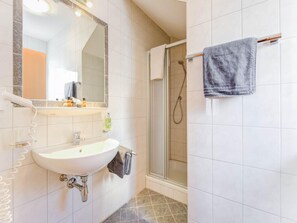 A bathroom with a white sink, a mirror, a shower, and a towel rack. - Apartment in Tyrol in an Attractive Area (Fiss)