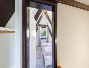 A narrow corridor leading to a bedroom with a bed and a window. - Nurdachhaus in Burhave (Butjadingen)