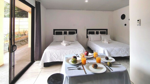A hotel room with two beds, a dining table with breakfast items, and a sliding glass door to the outside. - Studio/Pool/WIFI-Full kitchen-A/C-Large Beach-Sunset-Surf***. (Playa Grande)