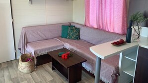 A cozy living room with a sofa, a coffee table, a small table with a plant, and a shelf with decorative items. - Comfortable Seaside Home in Conil (Vejer de la Frontera)