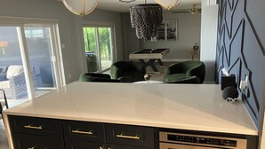 A modern kitchen with a large island, black cabinetry, gold handles, and a built-in dishwasher and oven. - Open water 3bdrm 3bath home with dock for 20 foot boat along with pool & jacuzzi (St. Petersburg)
