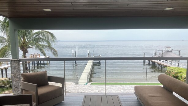 A covered outdoor seating area with a view of the sea and a dock. - Open water 3bdrm 3bath home with dock for 20 foot boat along with pool & jacuzzi (St. Petersburg)
