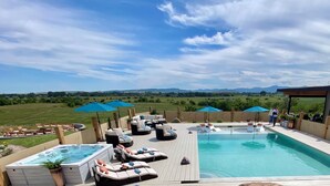 Une piscine sur le toit, avec des chaises longues, des parasols et un jacuzzi.