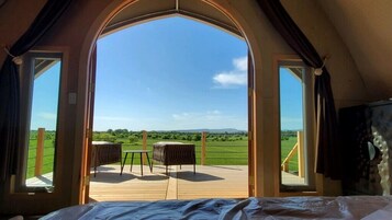 Un dormitorio con un ventanal grande, una cama y vistas a una terraza con sillas.
