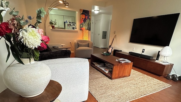 A modern living room with a sofa, coffee table, TV, and decorative items. - Serene 2-bedroom apartment with AC in vibrant Bronx neighborhood (bronx)