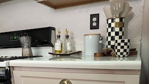 A kitchen with white cabinets, a stove, and a checkered bowl on the countertop. - Serene 2-bedroom apartment with AC in vibrant Bronx neighborhood (bronx)