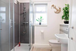 Un baño moderno con ducha envuelta en vidrio, inodoro y lavamanos.