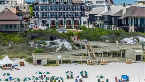 A beachfront hotel with a prominent tower, a wooden boardwalk, and beach umbrellas. - Walk to Rosemary, Resort Pool, Bikes, Beach Gear (Panama City Beach)