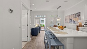 A modern kitchen with a large island, bar stools, and a view to the outdoor patio. - Walk to Rosemary, Resort Pool, Bikes, Beach Gear (Panama City Beach)