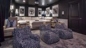 Una sala de estar acogedora con un sofá modular, un reposapiés estampado de cebra y cuadros en la pared.