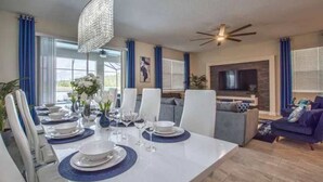 Un comedor moderno con una mesa blanca dispuesta para seis personas, rodeada de sillas blancas.