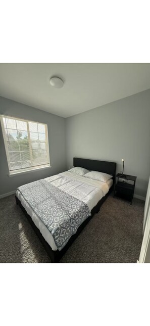 A bedroom with a bed, a nightstand, a window, and a ceiling light. - CENTRAL DENVER FAMILY HOME (Denver)