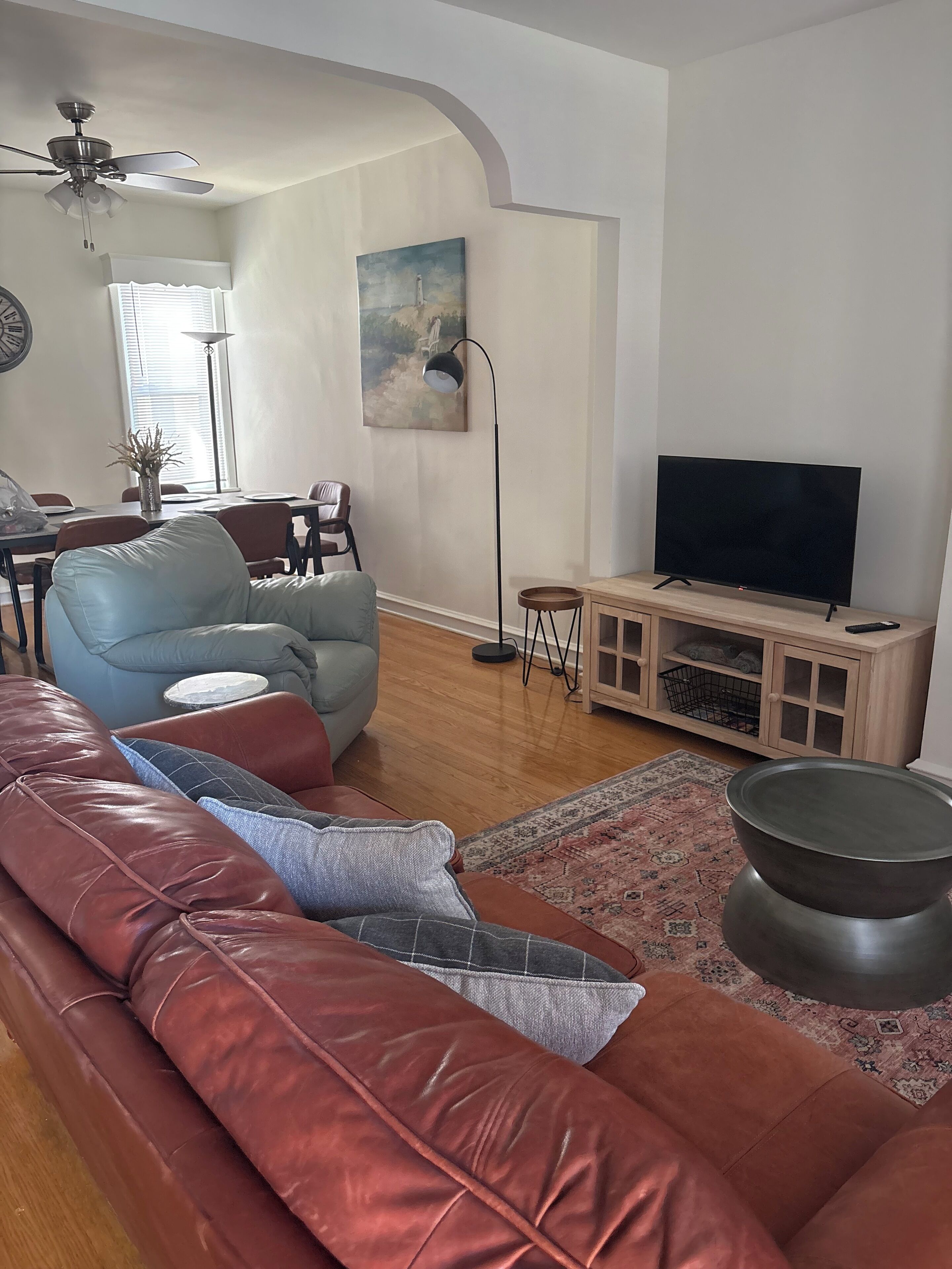 Un salon avec un canapé, un téléviseur, une lampe sur pied et un tableau accroché au mur.