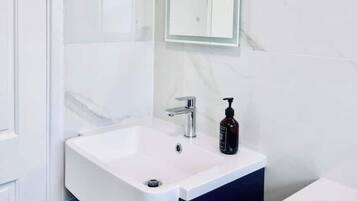 Een badkamer met een wit wastafelmeubel, donkere kastjes en een marmeren wand.