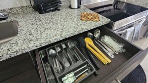 A kitchen with dark cabinets, a granite countertop, a built-in oven, and a drawer organizer with utensils. - Portmore Paradise: Pool & 24/7 Security (Portmore)