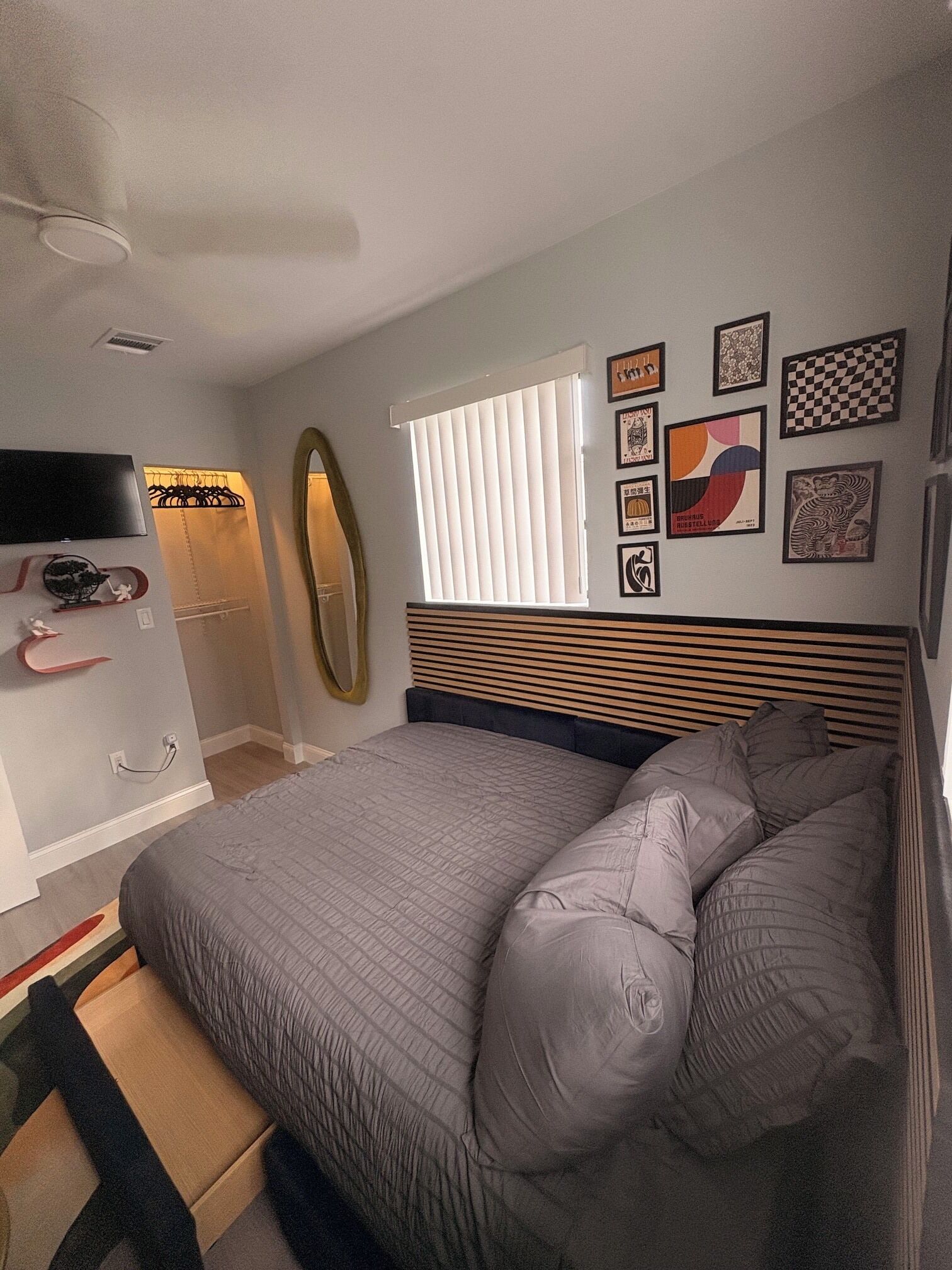 A bedroom with a bed, a wardrobe, a mirror, and wall art.